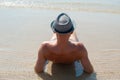 Stylish young male model man lying on beach sand wearing hipster summer hat enjoying summer travel holiday near the sea Royalty Free Stock Photo