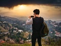 Male photographer or tourist standing against mountain town