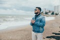 Stylish young man with a beard standing near ocean with a cup of tea Royalty Free Stock Photo