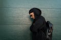 Stylish young man in a black fashionable hooded sweatshirt with a stylish leather black  backpack in sunglasses in a trendy cap Royalty Free Stock Photo