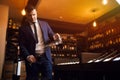 Stylish young man in blue suit and white shirt pouring wine from decanter