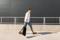 Stylish young man hipster in fashionable clothes in leather sandals with a fabric bag in sunglasses walks on the street Royalty Free Stock Photo