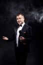 Stylish young man holding microphone, posing on dark background, actor, singer, show, host of event Royalty Free Stock Photo