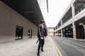 Stylish young man in an oversize leather jacket in vintage pants in cool boots with a fashionable black backpack walks on the Royalty Free Stock Photo