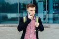 Stylish young man in plaid shirt with backpack walking in the city Royalty Free Stock Photo