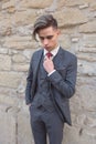 Stylish young man with a suit arranges his tie