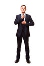 Stylish young man in suit and tie. Business style. Handsome man is standing, looking at the camera and fixing his tie