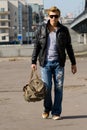Stylish young man walks with big travel bag