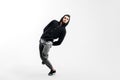 Stylish young man wearing a black sweatshirt and gray pants is dancing street dances on a white background Royalty Free Stock Photo