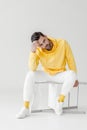 stylish young man in yellow hoodie sitting on flipped chair