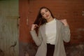 Stylish young pretty girl in a gray coat looks at the camera and smiles slightly against the background of the city Royalty Free Stock Photo