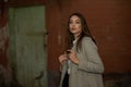 Stylish young pretty girl in a gray coat looks at the camera and smiles slightly against the background of the city Royalty Free Stock Photo