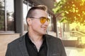 Stylish young smiling guy businessman of Caucasian appearance portrait in sunglasses, jacket and shirt on the street outdoor Royalty Free Stock Photo