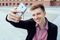 Stylish young smiling man in plaid shirt making selfie outdoors. Royalty Free Stock Photo