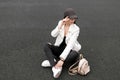 Stylish young woman in black ripped jeans in a leather jacket in a t-shirt with a gold backpack in fashionable sneakers Royalty Free Stock Photo