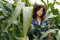 Stylish young woman in blue vintage dress and hat posing in green corn field. Sensual portrait of beautiful girl in cornfield maze
