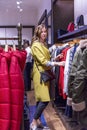 Stylish young woman in a bright yellow coat in a fashion store in the autumn earth season. Vertical Royalty Free Stock Photo