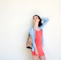 Stylish young woman carrying a purse leaning against wall Royalty Free Stock Photo