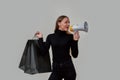 Stylish young caucasian woman dressed in black looking away and screaming in megaphone, making sale announcement, posing Royalty Free Stock Photo