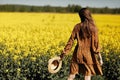 Stylish young woman in a field of yellow flowers. Girl in straw hat and in a floral dress. place for inscription Royalty Free Stock Photo