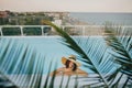 Stylish young woman in hat relaxing in pool under palm leaves and enjoying summer holiday. Summer vacation. Girl in sunhat on Royalty Free Stock Photo