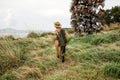 Stylish young woman in khaki shirt walking in steppie, traveling in Africa on safari, wearing hat and brown backpack Royalty Free Stock Photo