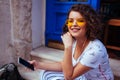 Stylish young woman listening to the music using smartphone. Outdoor portrait of fashionable girl wearing glasses Royalty Free Stock Photo
