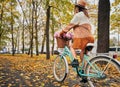 Stylish young woman riding bicycle with flowers on autumn street. Royalty Free Stock Photo