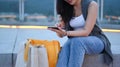 Stylish young woman sitting on stairs with shopping bags and using smart phone, resting after shopping Royalty Free Stock Photo