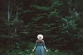 Stylish young woman in a straw hat and dress stands on a background of green forest and trees. Travel concept. Copy, empty space Royalty Free Stock Photo