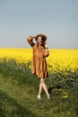 Stylish young woman in straw hat in a field of yellow flowers. Girl in a floral dress Royalty Free Stock Photo