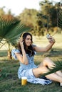 Stylish young woman in summer dress listening to music with headphones and take selfie on smartphone outdoor. Royalty Free Stock Photo