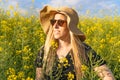 Stylish young woman in sun hat enjoying spring in yellow flowers, rapeseed field at sunset Royalty Free Stock Photo