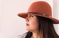 Stylish young woman wearing a brown fedora hat, looking off to the side with confidence