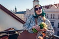 Stylish young woman wearing green retro shawl with sunglasses holding spring flowers in city. Classic vintage fashion Royalty Free Stock Photo