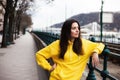 Stylish young woman in yellow hoody posing in the city streets.