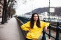 Stylish young woman in yellow hoody posing in the city streets.