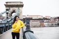 Stylish young woman in yellow hoody posing in the city streets.