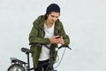 Stylish youngster in black hat and jacket with hood, has active lifestyle, covers long distances with his sport bicycle, has break