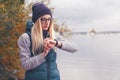 Stylishly dressed blonde sportswoman adjusts an electronic bracelet-pedometer standing on the lake shore. Autumn sports