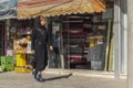 Stylishly dressed iranian woman in black hijab passes by fabric stores in the eastern bazaar