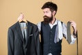Stylist advice. Matching necktie with outfit. Man bearded hipster hold neckties and formal suit. Guy choosing necktie