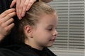 Stylist hairdresser. creates a hairstyle for the evening, little girl, stabs hair with a hairpin, baby smiles Royalty Free Stock Photo