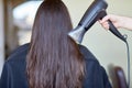 Stylist hand with fan dries woman hair at salon