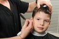 Stylist makes the boy a hairstyle in the beauty salon