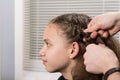 Stylist makes a hairstyle from the braid girl in the beauty salon