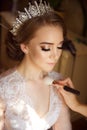 Stylist makes makeup bride on the wedding day. Makeup artist preparing beautiful girl before wedding, in morning