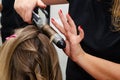 Stylist making a hairdo with hair curler. Beauty salon