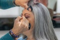 Stylist placing eyebrow makeup in a professional makeup session on a senior adult woman