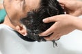 Stylist washing client`s hair at sink in beauty salon Royalty Free Stock Photo